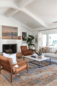 mid century modern living room with white walls and light tan sofa. there are also cognac leather armchairs and a marble and metal coffee table